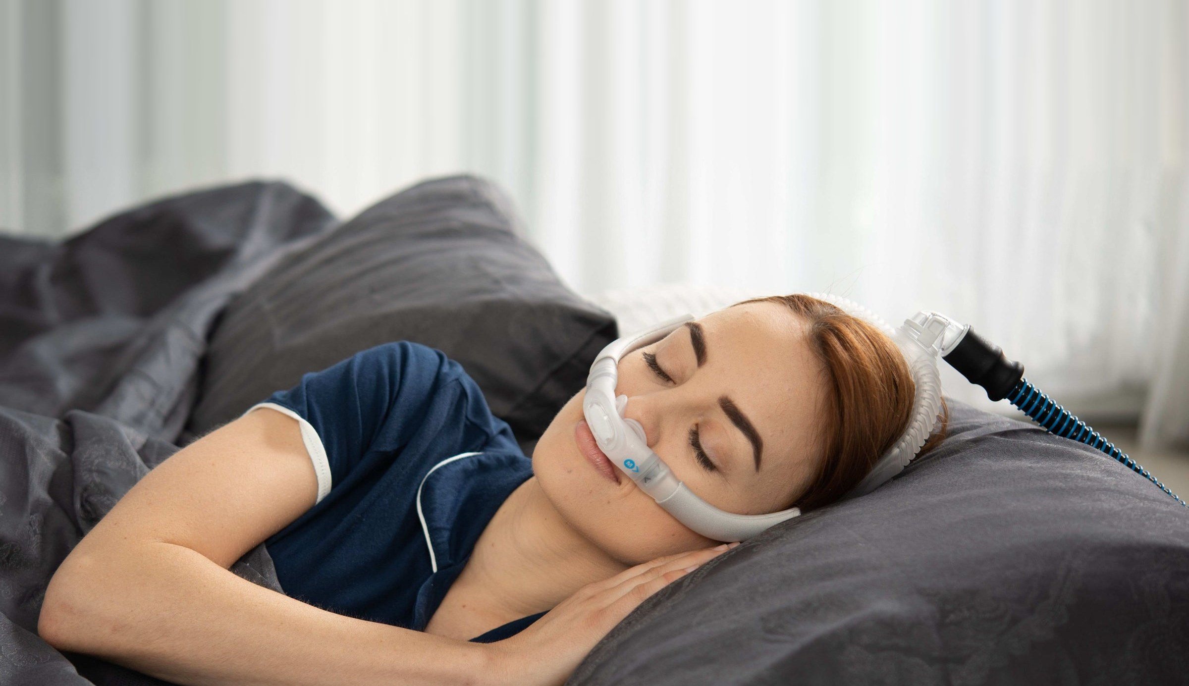 Woman sleeping peacefully with a nasal CPAP mask